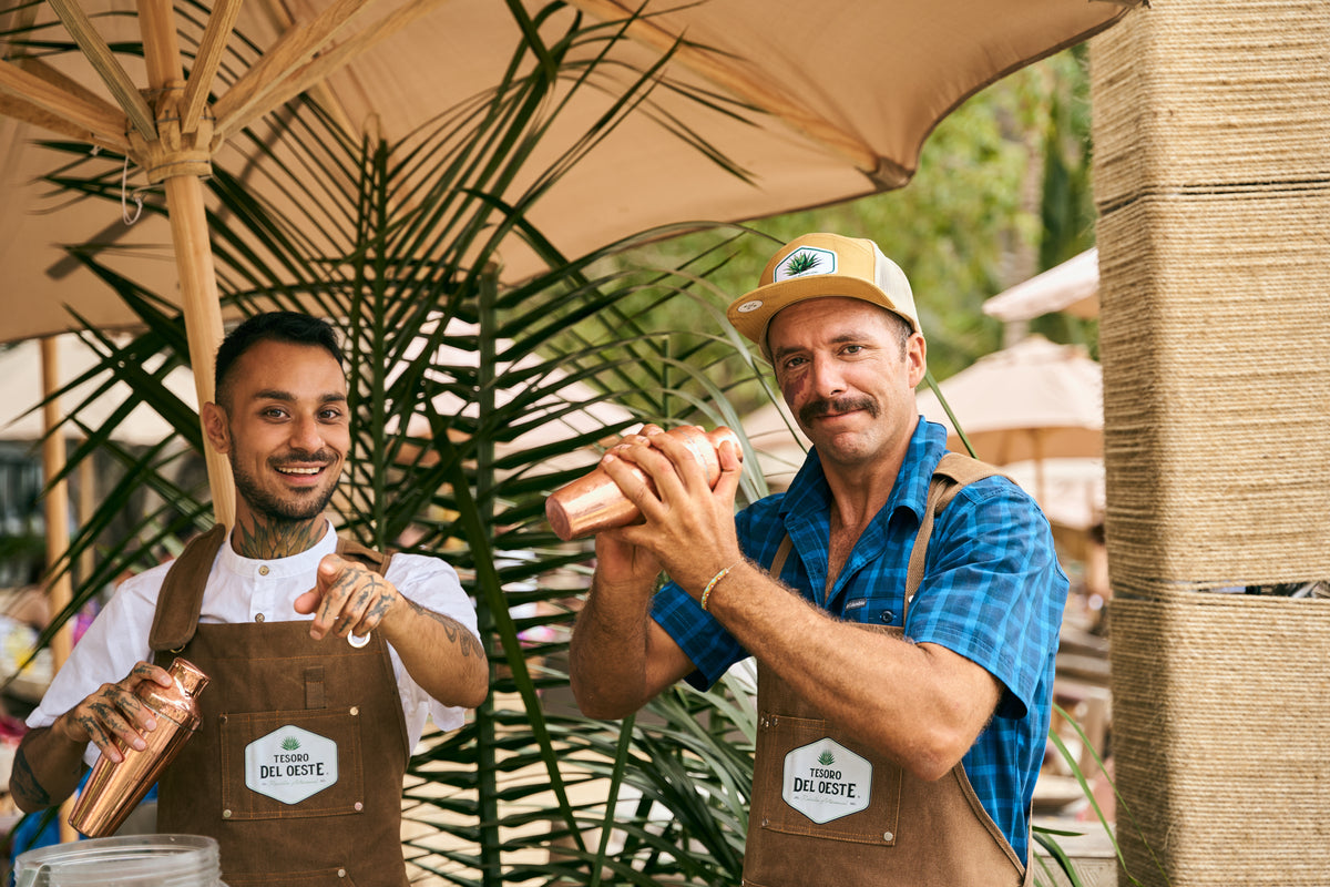 Anfitriones de Tesoro del Oeste preparando cocteles de raicilla en un evento